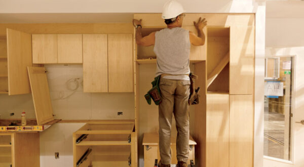 Blu Homes Construction - Founders Bill Haney & Maura McCarthy at their East Longmeadow, MA manufactory.  Tom Skala, Carpenter, installs kitchen cabinet units on a house nearing completion.